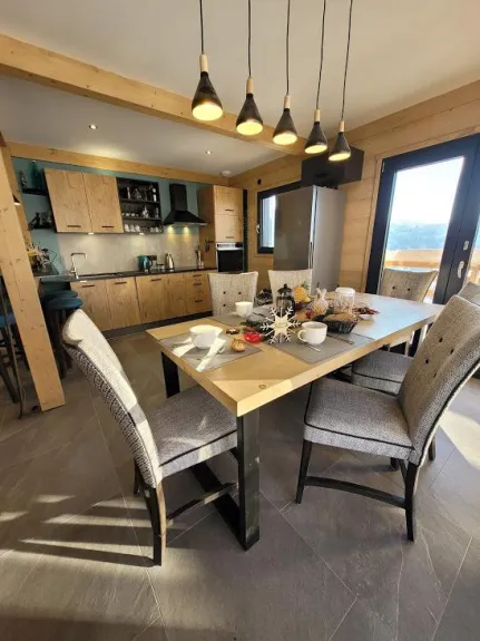 coin séjour ,ouvert sur cuisine , table massive bois ,accès balcon et terrasse avec vus sur les montagnes plein sud ,