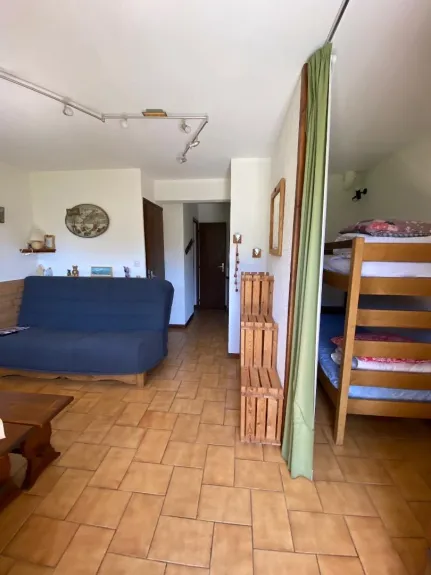 Vue général du studio à droite la pièce à vivre avec le coin repas et le canapé lit pratiquement neuf très confortable, à droite les lits superposés dans cabine, au fond salle de douche, wc et cuisine à droite.
