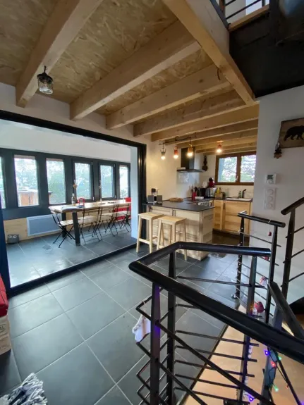 Vue du séjour vers la cuisine , cage d'escaliers et véranda R+1
