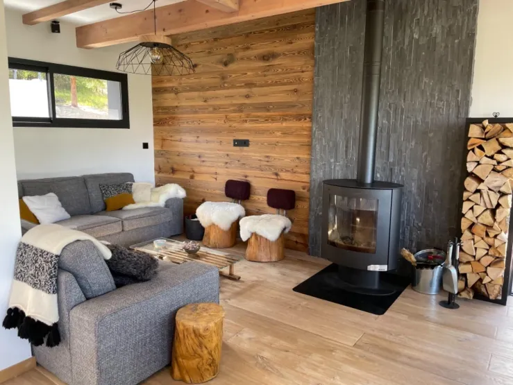 Bienvenue dans notre chalet ! Son point fort : la luminosité et sa déco chaleureuse. Il est aussi très bien conçu, on s'y sent aussi bien à 2 qu'à 10. Ici, le coin salon avec le poêle à bois.