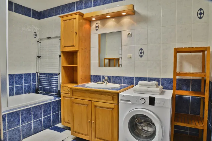 Salle de bains avec baignoire utilisable en douche, lave linge.