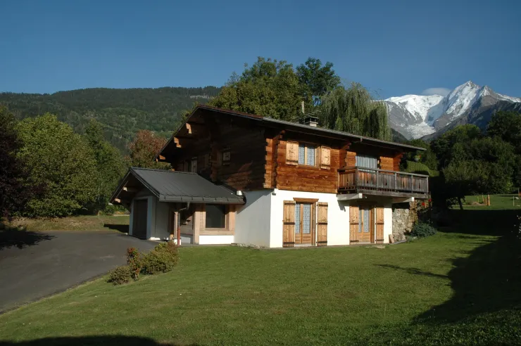 The chalet, set amongst greenery, with views of the Mont Blanc massif