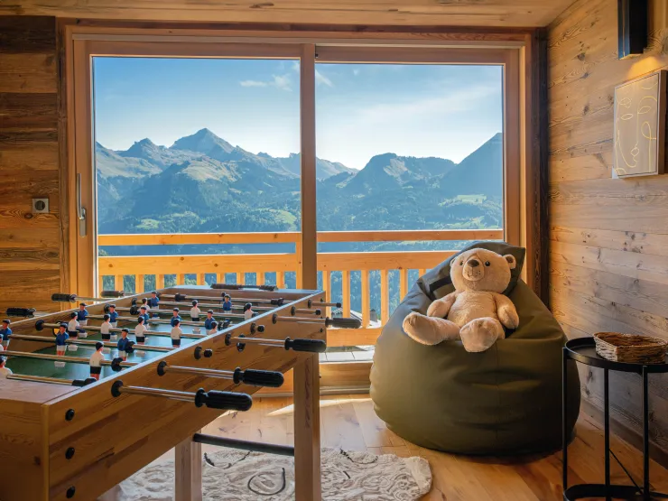 Relaxation area with a foosball table and an open view of the Alps. A warm space where both kids and adults enjoy playful moments with a stunning mountain backdrop.