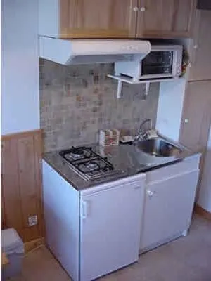 Le coin cuisine, réfrigérateur, mini-four, hote aspirante, placards de rangement.