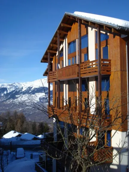 View of the residence on winter, taken from the side of the slopes. Balcony at the top center.