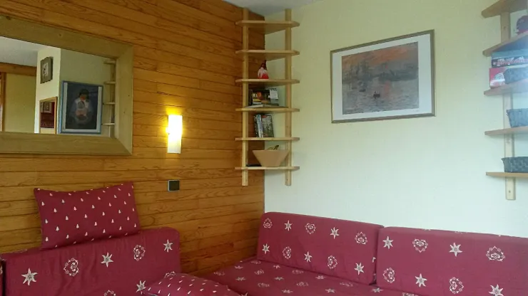 Living room with painting reproductions of Monet and Toffoli ; shelves with DVDs (5 for all ages), board games, cards, chess, mikado..