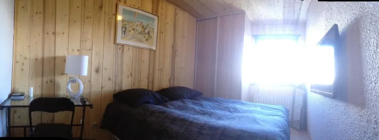 Sleeping room with king size bed, flat screen, large cupboard and table