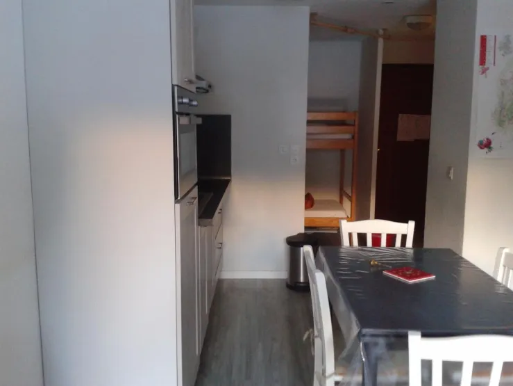 table avec rallonges pour 6 personnes  ;  au fond derrière un rideau 2 lits 1 pers superposés