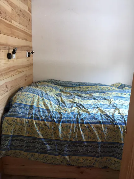 Le lit en 140 dans la chambre. Il est monté sur vérin, ainsi vous accédez facilement à un espace de rangement pour les valises sous le lit