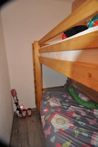 Deux lits superposés dans une pièce fermée. Sous le lit, deux tiroirs. en bout de lits, des rangements, une penderie enfant. 