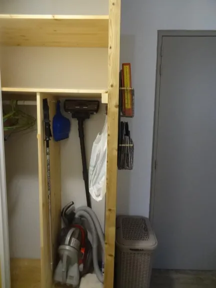 Storage lockers and vacuum cleaner, brooms. We see the front door and the documentary lockers