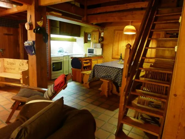 Séjour : Le coin cuisine américaine  , sa table pour huit personnes  et l'escalier d'accès à la chambre en mezzanine 