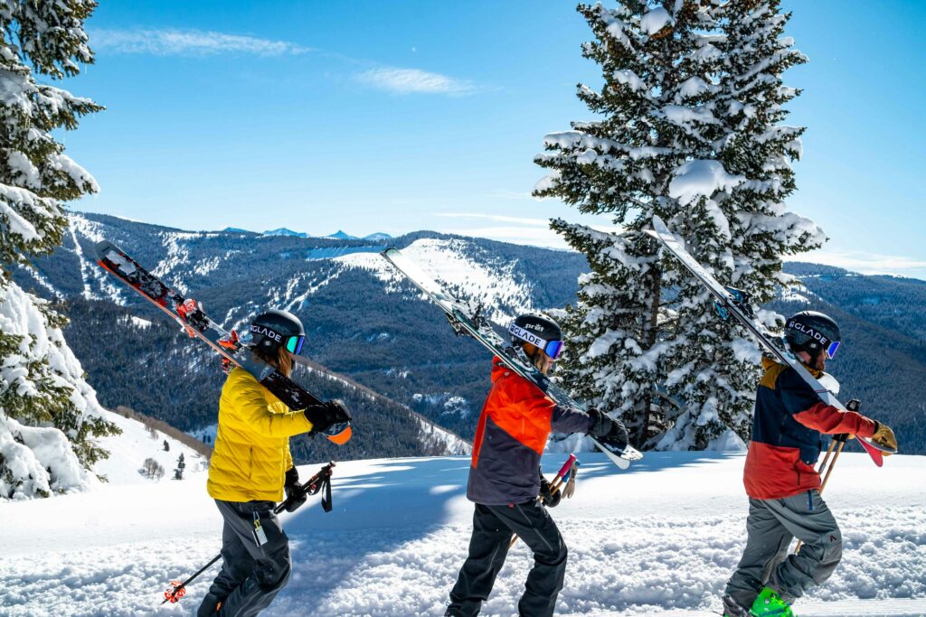 trois skieurs qui marchent avec leurs skis sur l'épaule